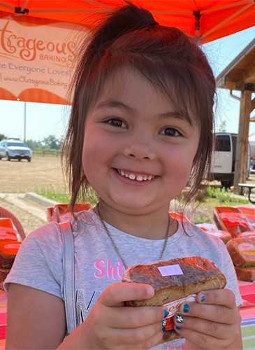 cute girl with brown hair holding gluten free bread at the farmers market